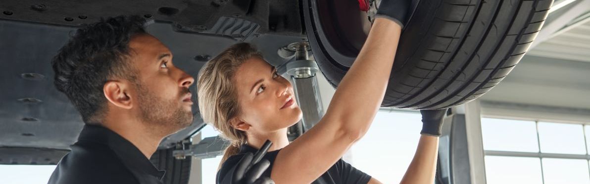 Zwei Audi Mechaniker kontrollieren die Radaufhängung bei einem Audi