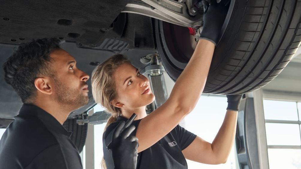 Zwei Audi Mechaniker kontrollieren die Radaufhängung bei einem Audi