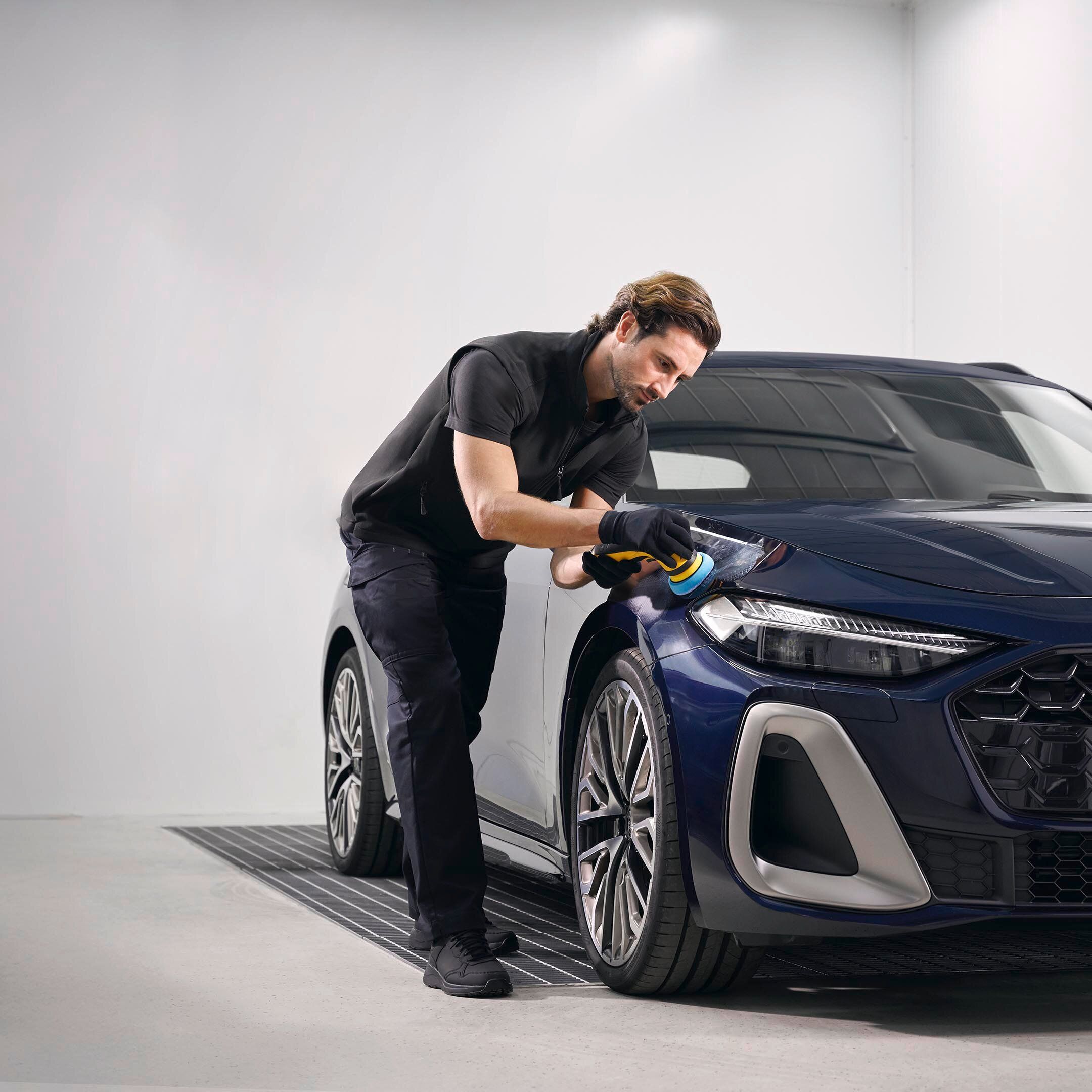 Ein Audi Techniker poliert Lack bei einem Audi