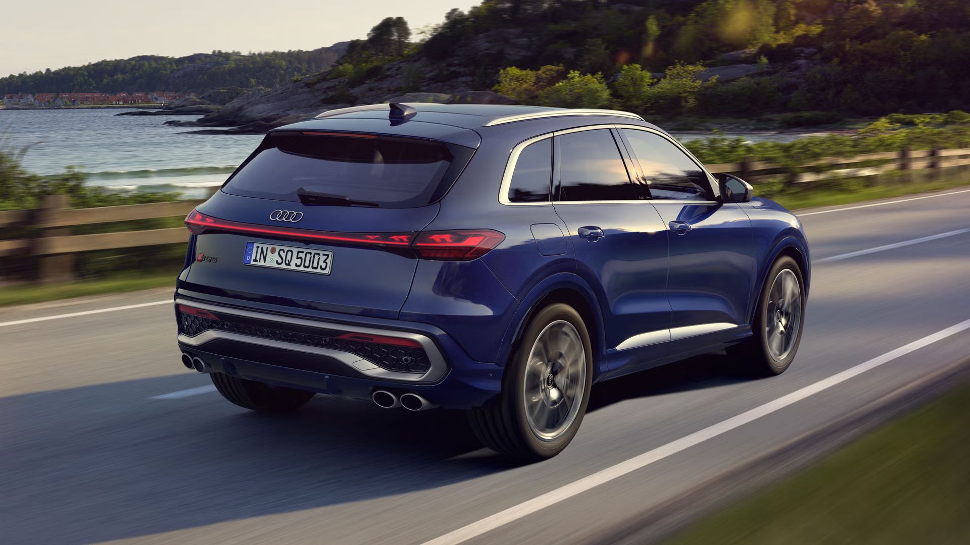 Der SQ5 SUV in dunkelblau, welcher auf einer Straße entlang der Küste fährt.