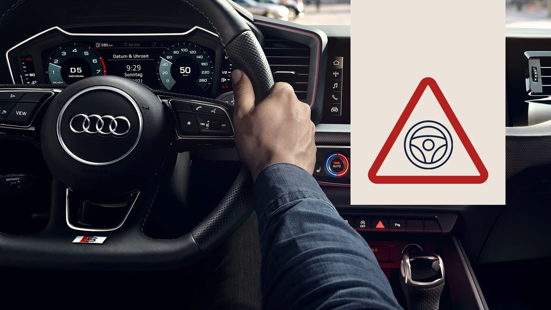 Innenansicht eines Audi-Cockpits, bei dem eine Hand das Lenkrad hält und das digitale Armaturenbrett mit Tacho und weiteren Anzeigen zu sehen ist. Rechts im Bild ist ein eingeblendetes dreieckiges Warnsymbol mit einem Lenkrad-Piktogramm.