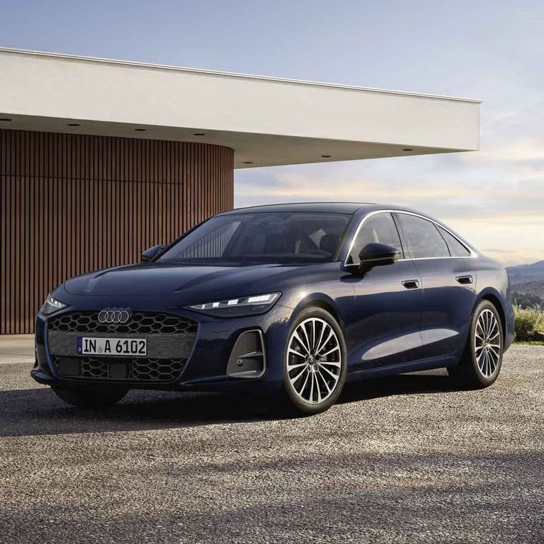 Die A6 Limousine steht im schrägen Frontprofil vor einem modernen Haus. 