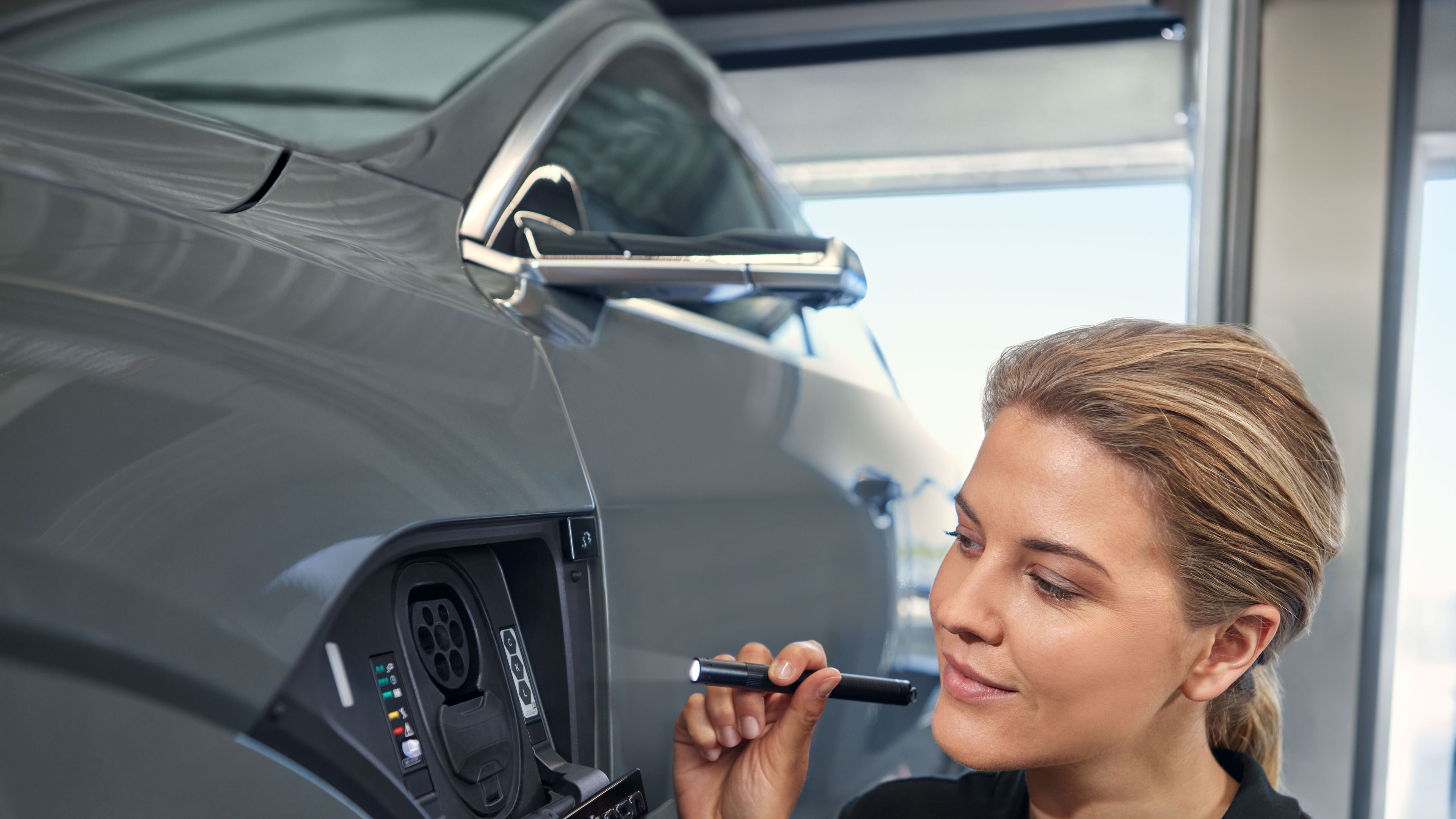 Eine Audi Service Technikerin überprüft den Ladeanschluss eine Audi Elektroautos
