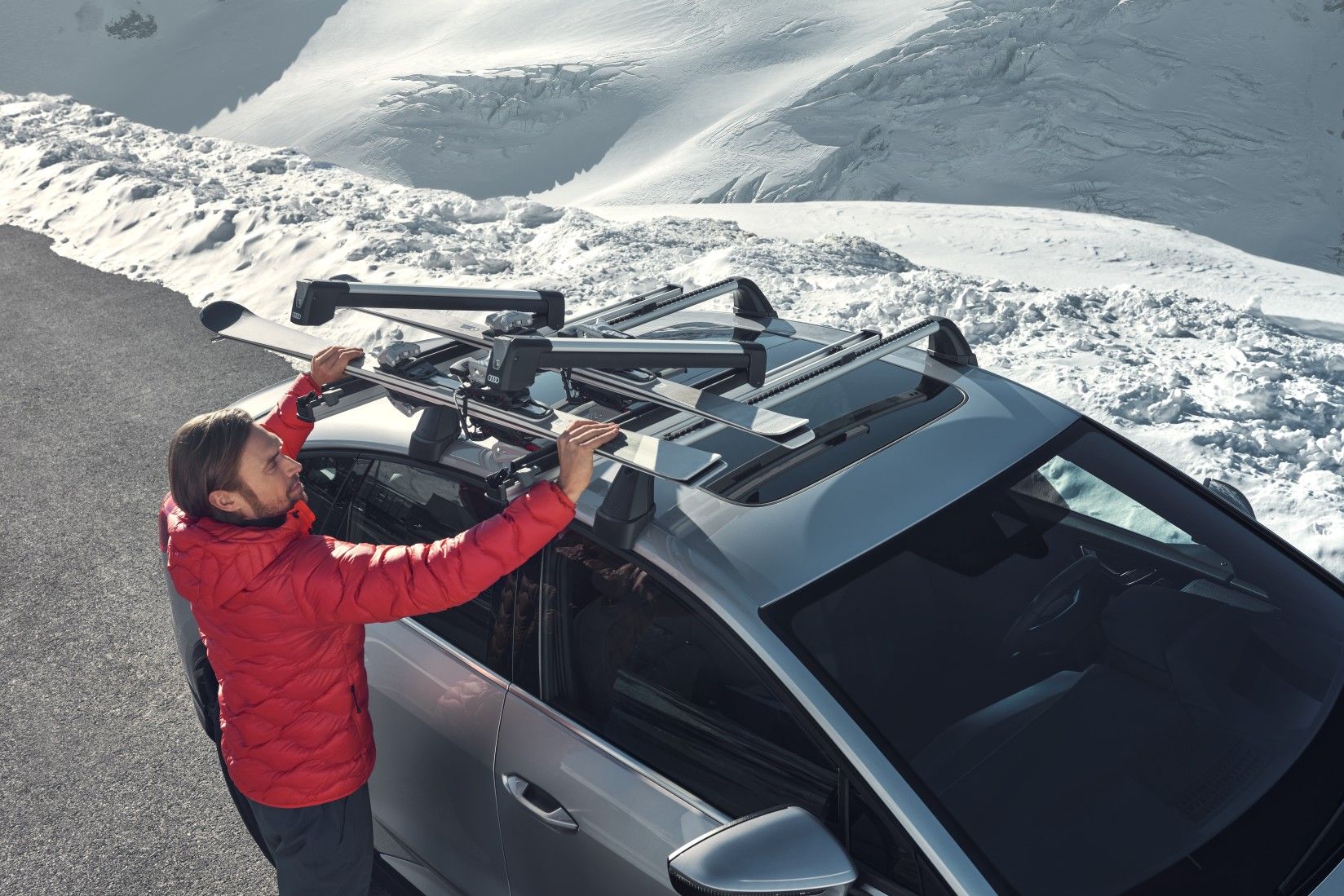 Mann befestigt Ski am Skihalter auf dem Dach eines Audi Q4 Sportback e-tron