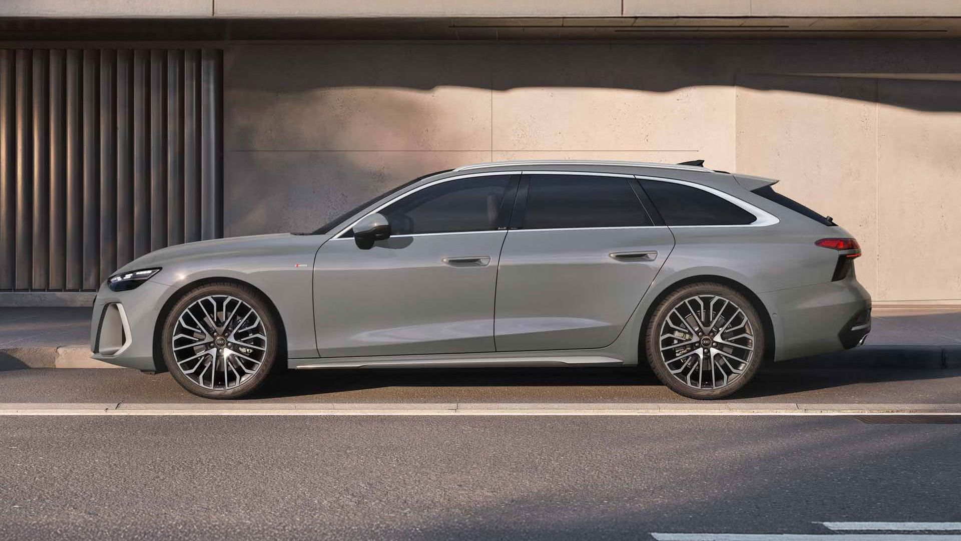 Der A6 Avant steht im Seitenprofil mit einer grauen Lackierung in einer Parkbucht vor der Fassade eines Gebäudes.