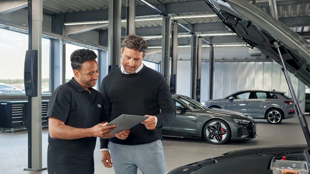 Ein Audi Service Techniker im Gespräch mit einem Kunden.