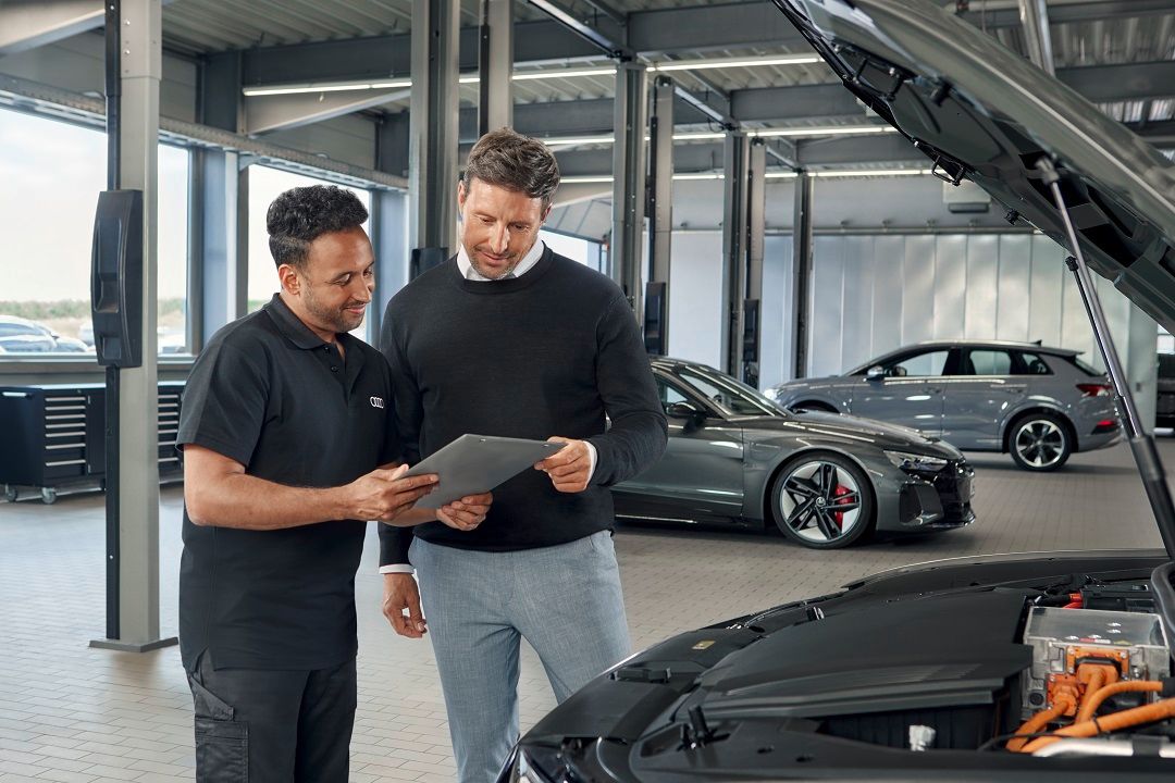 Ein Audi Service Techniker im Gespräch mit einem Kunden.