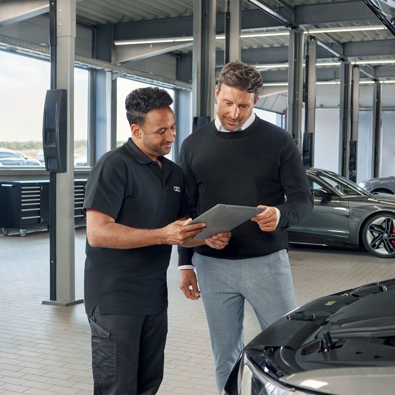 Ein Audi Service Techniker im Gespräch mit einem Kunden.