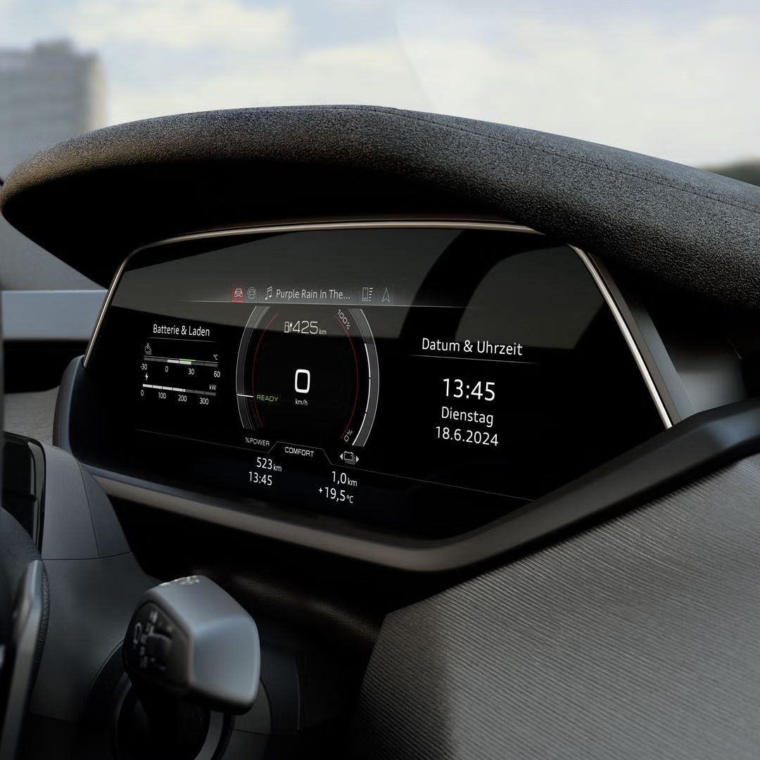 Nahaufnahme des digitalen Cockpits eines Audi S e-tron GT mit Tachometer, Batteriestatusanzeige und Datum/Uhrzeit. Das Display zeigt eine verbleibende Reichweite von 425 km und spielt das Lied „Purple Rain“.