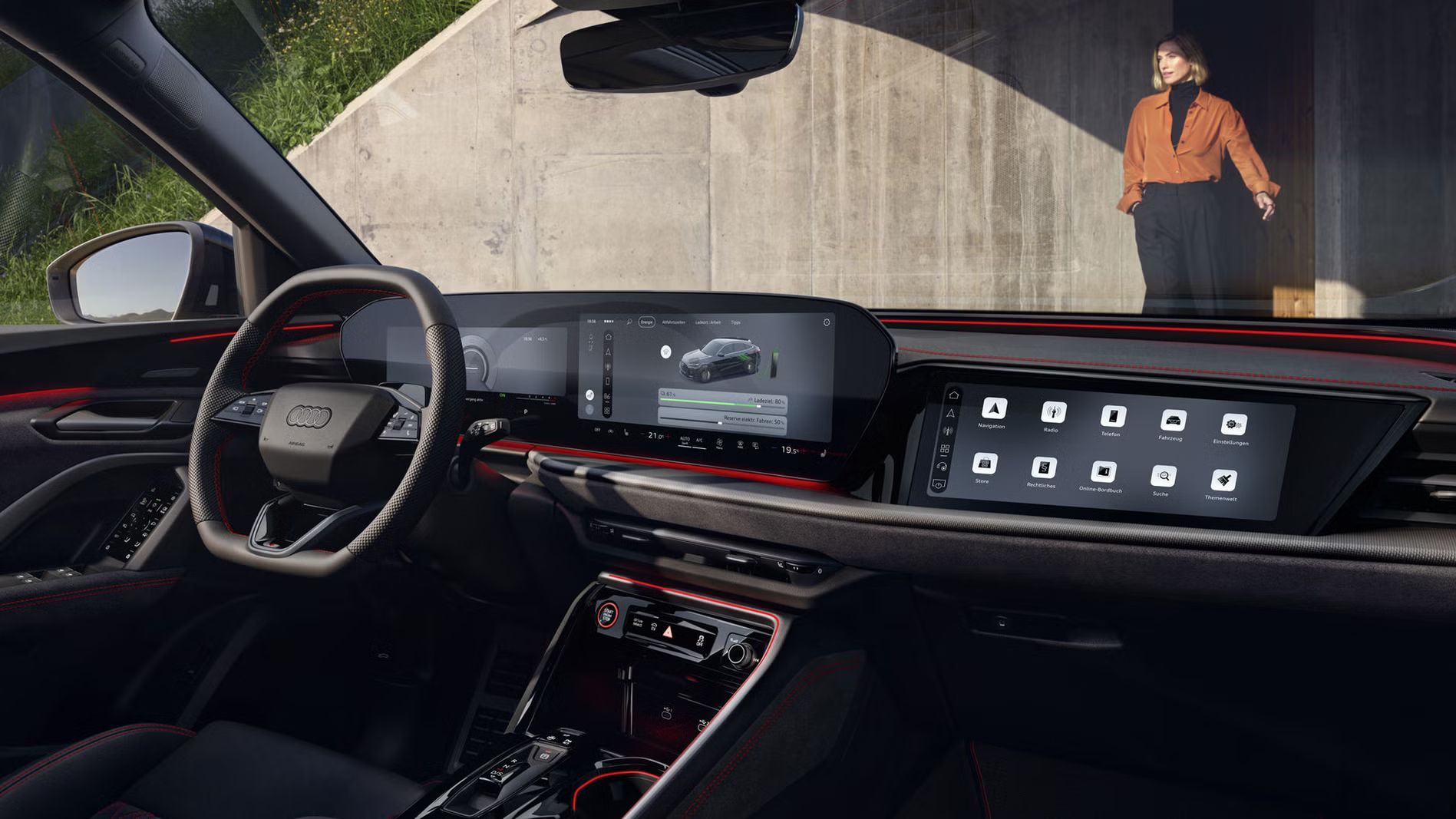 Der Innenraum des Q5 Sportback e-hybrid mit Fokus auf das Lenkrad und die digitalen Displays. Vor dem Fahrzeug steht eine modisch gekleidete, junge Frau.
