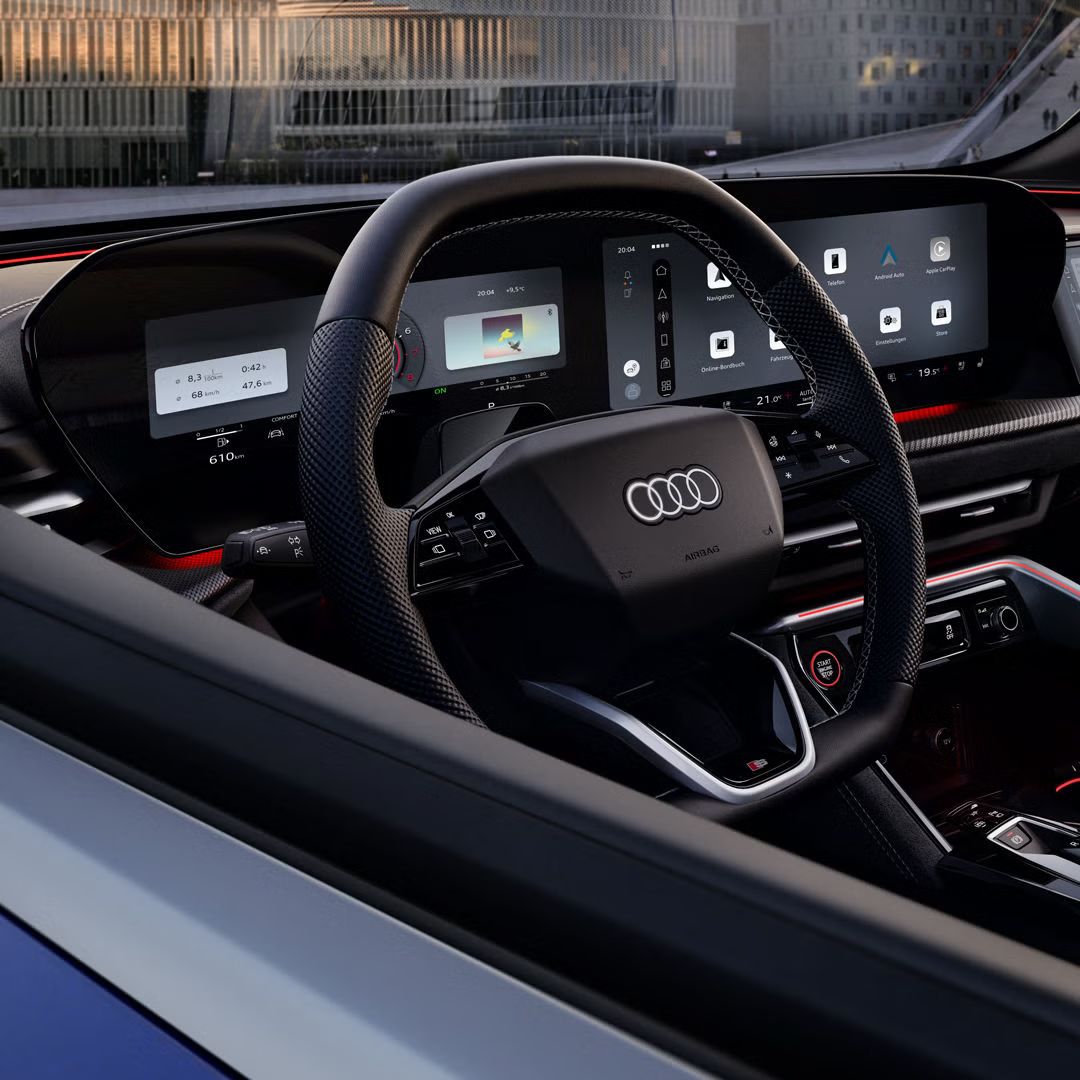 Blick durch das Fahrerfenster in das Cockpit des SQ5 SUV. Im Fokus stehen das Lenkrad mit dem dahinter befindlichen Audi virtual Cockpit, sowie das MMI touch-Display.