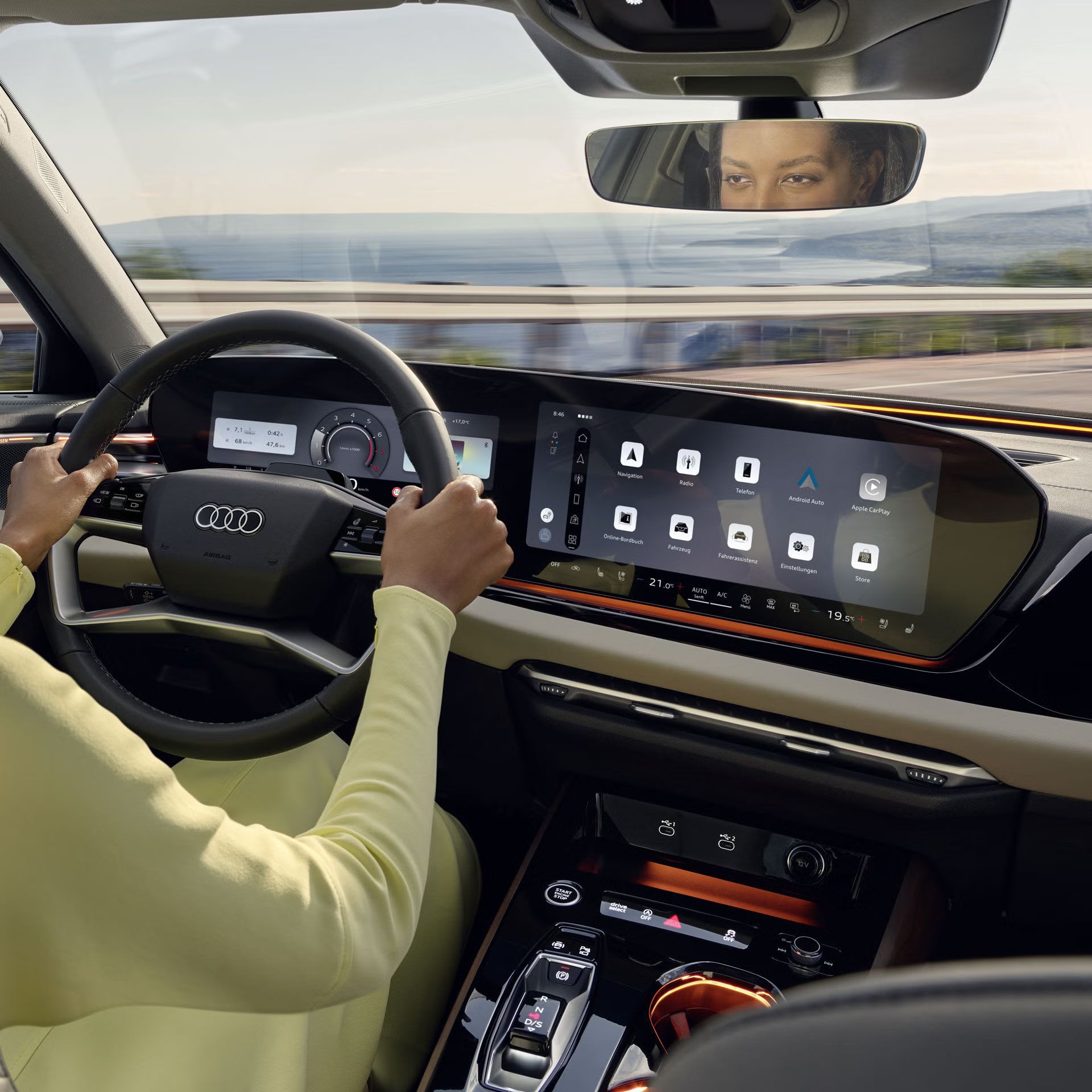 Blick von der Rückbank in das Cockpit der A5 Limousine. Eine Frau hält das Lenkrad in beiden Händen.