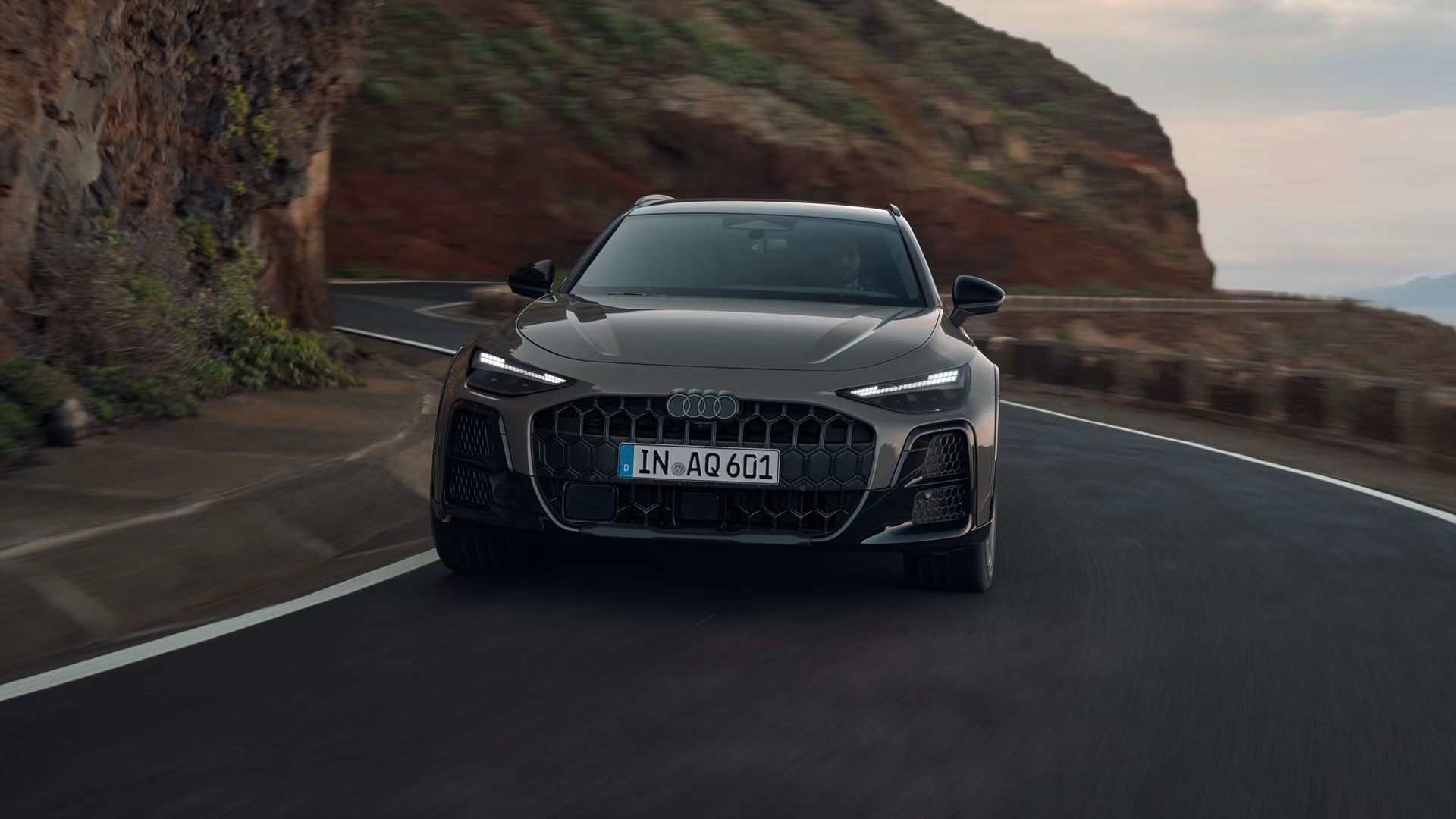 Der Audi A6 allroad von vorn auf durchfährt eine kurvige Gebirgsstraße. 
