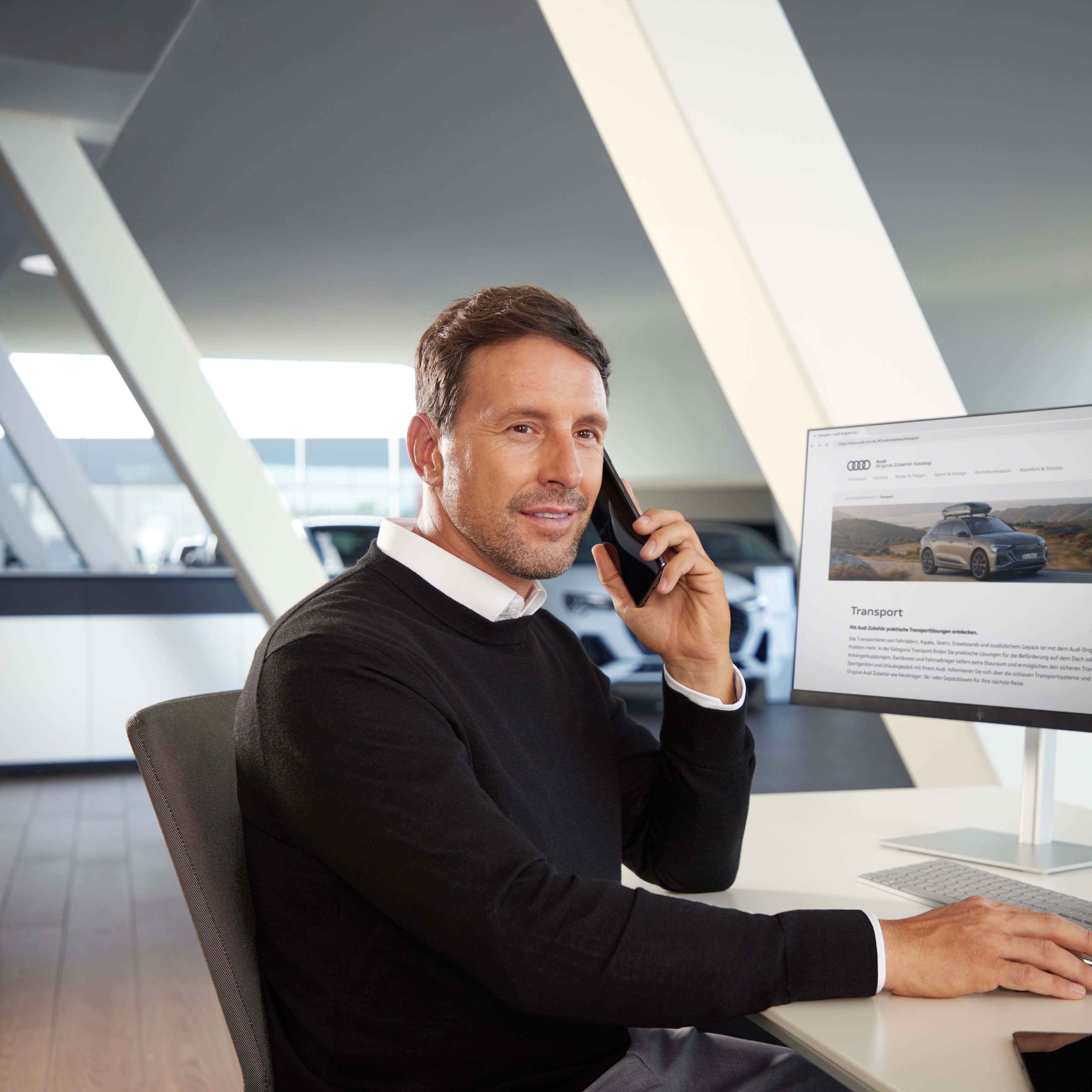 Serviceberater an seinem Arbeitsplatz mit mobilem Gerät, Bildschirm mit Anzeige