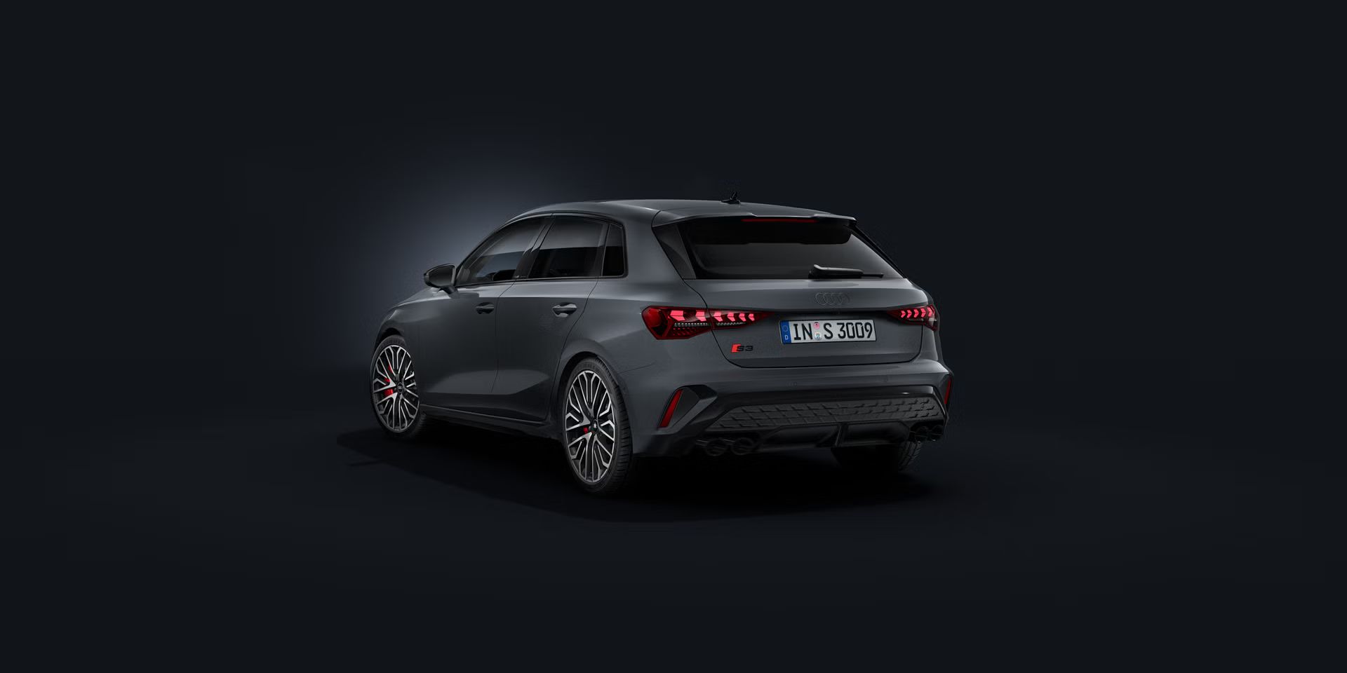 Der Audi S3 Sportback schräg von hinten auf dunklem Hintergrund.