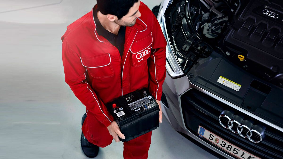 Ein Audi Service-Mitarbeiter trägt eine Audi Original Batterie 