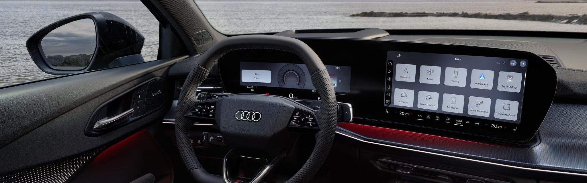 Blick von hinten auf das Cockpit des Q3 SUV mit Lenkrad, Panoramadisplay und rotem Ambiente-Lichtpaket. Durch die Frontscheibe ist das Meer zu sehen.