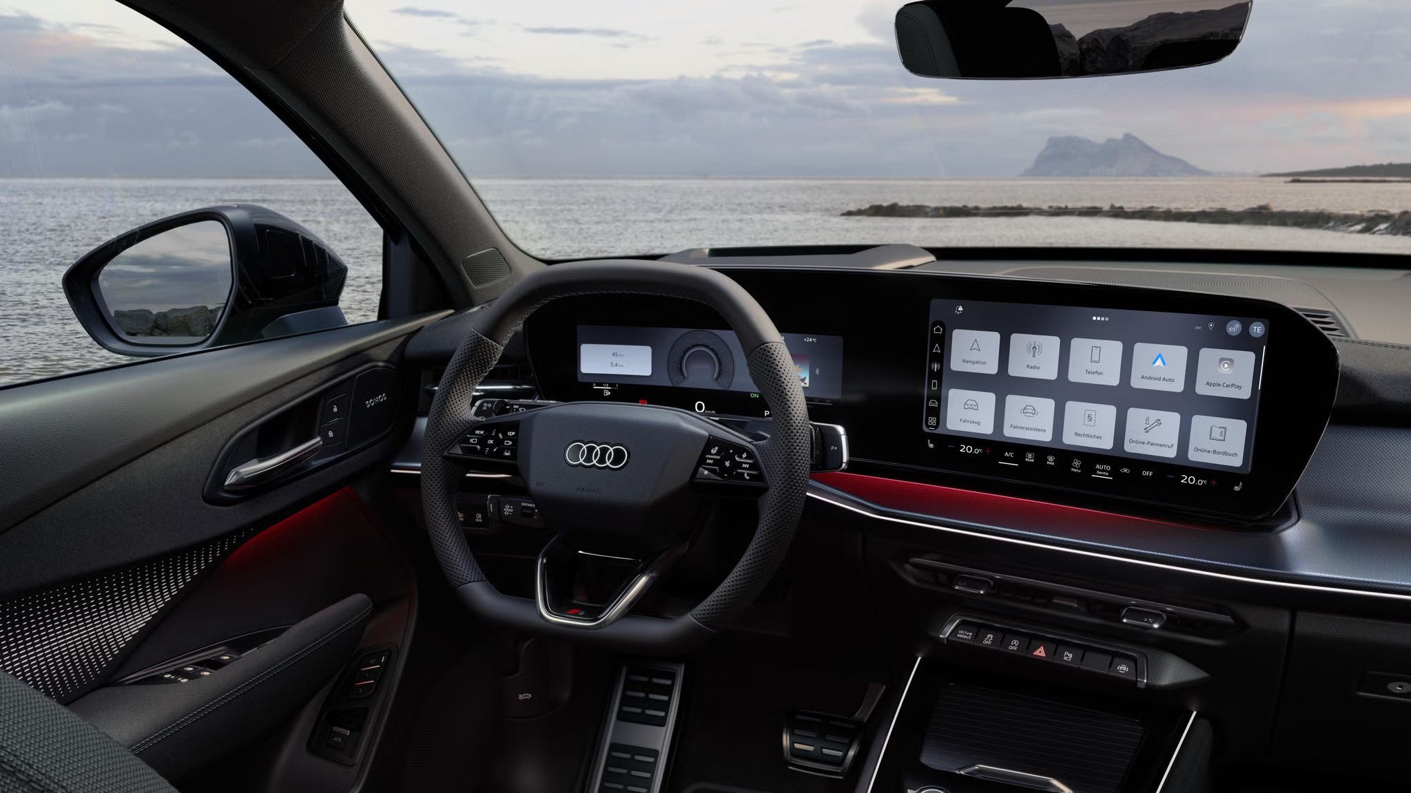 Blick von hinten auf das Cockpit des Q3 SUV mit Lenkrad, Panoramadisplay und rotem Ambiente-Lichtpaket. Durch die Frontscheibe ist das Meer zu sehen.