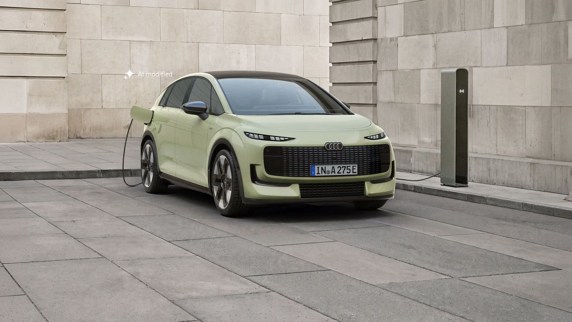 Der Audi A2 e-tron, frontal von hinten fotografiert, parkt vor einem modernen Gebäude. Das Fahrzeug ist an eine Ladesäule angeschlossen.
