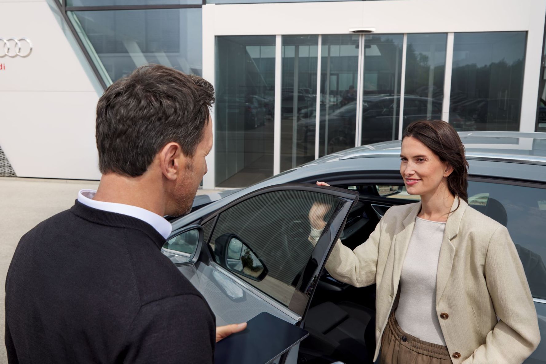 Frau erhält Informationen und Schlüssel zu einem Audi von einem Audi Mitarbeiter.