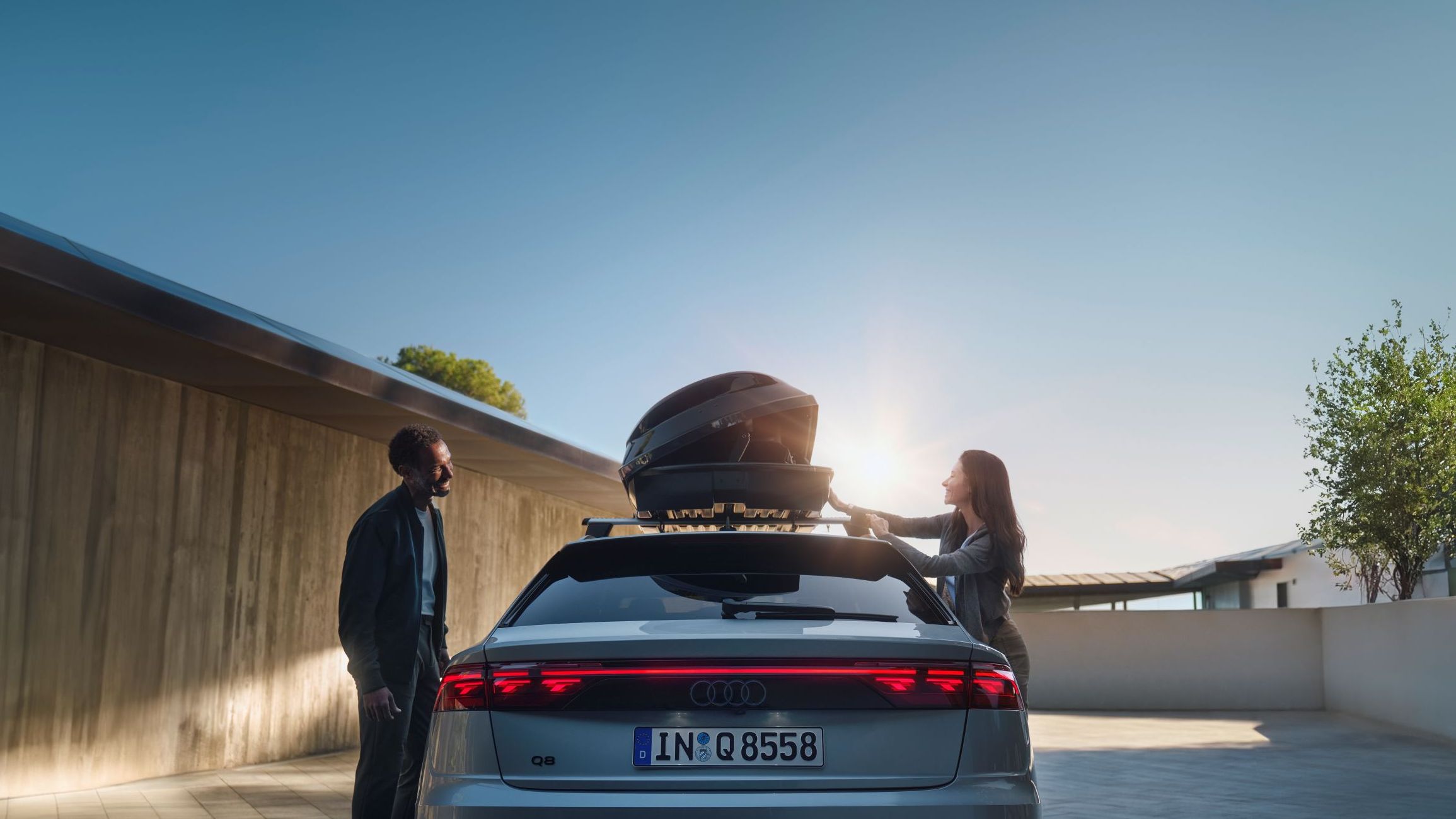Ein Audi Q8 mit geöffneter Dachbox auf dem Dach.