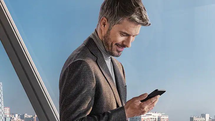 Ein Mann bedient lächelnd sein Smartphone