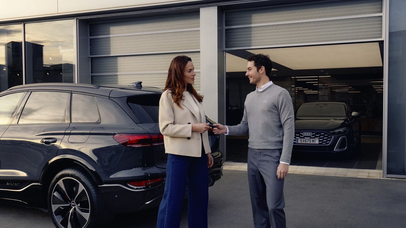 Ein Audi Mitarbeiter übergibt einer Kundin die Autoschlüssel für ihren Audi.