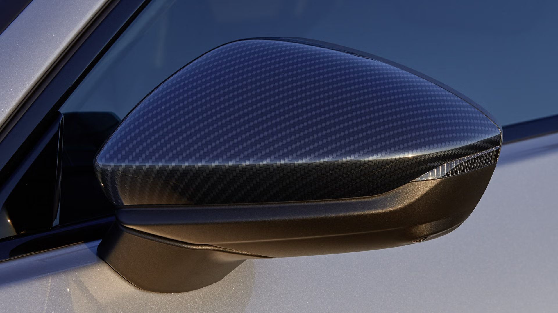 Nahaufnahme des linken Außenspiegels mit einem Gehäuse in Carbon.