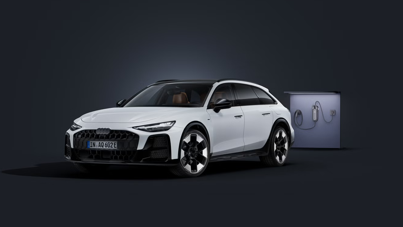 Der Audi A6 allroad e-hybrid schräg von vorne auf dunklem Hintergrund. Daneben eine moderne Ladesäule.