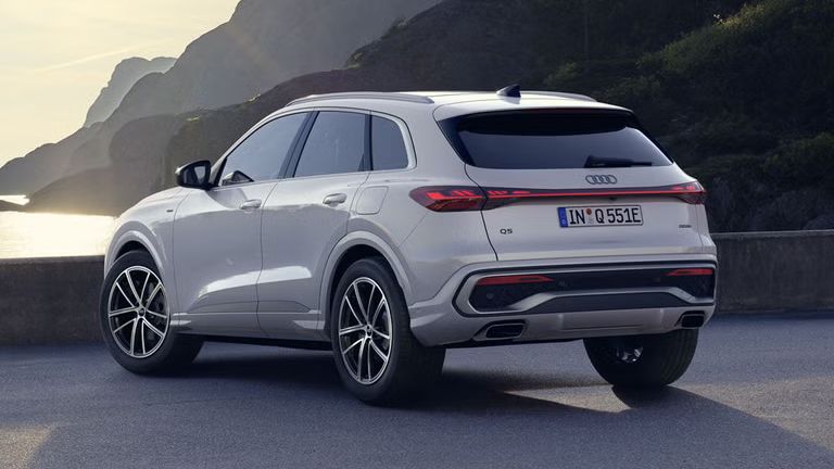 Ein weißer Q5 SUV e-hybrid steht auf einem Parkplatz an der Küste.