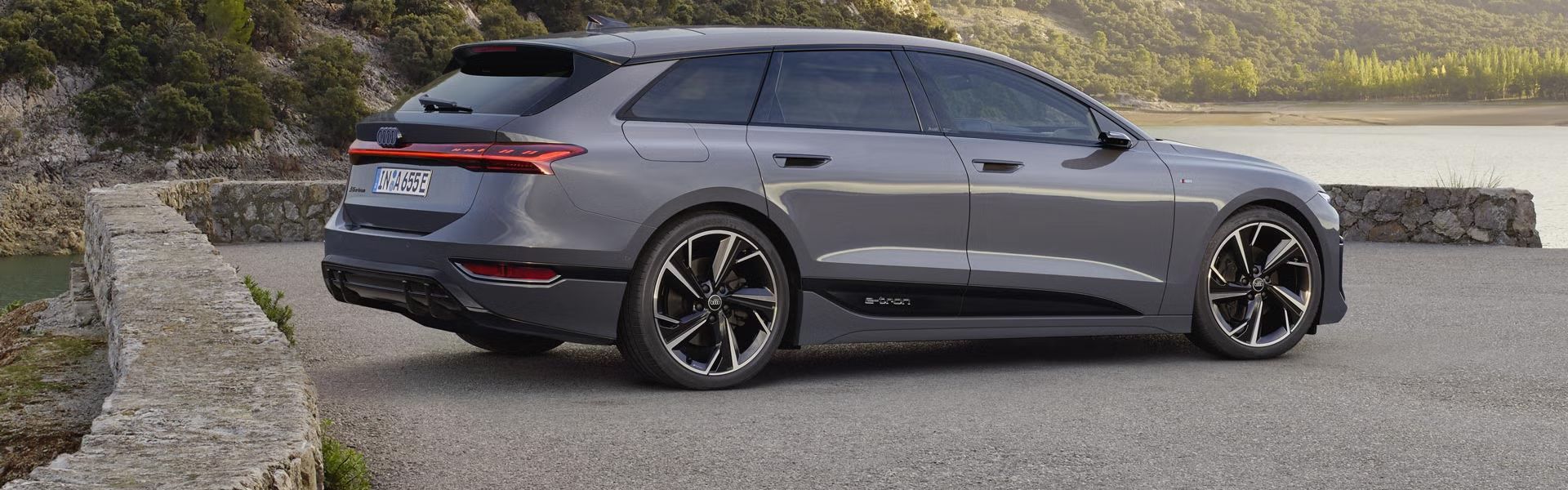 Ein grauer A6 Avant e-tron steht auf einem Platz vor einem Gewässer.