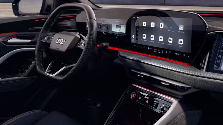 Blick durch das Beifahrerfenster in das Cockpit des SQ5 SUV. Zu sehen sind unter anderem das Panoramadisplay, das MMI Beifahrerdisplay, sowie die rote Ambiente Beleuchtung.