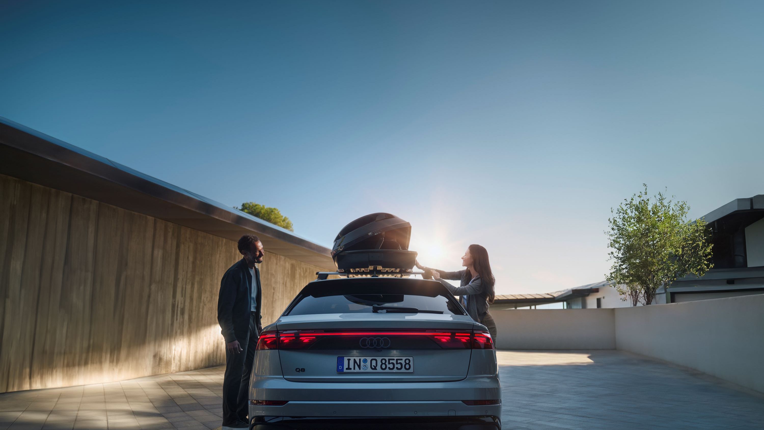 Ein Audi Q8 mit geöffneter Dachbox auf dem Dach.