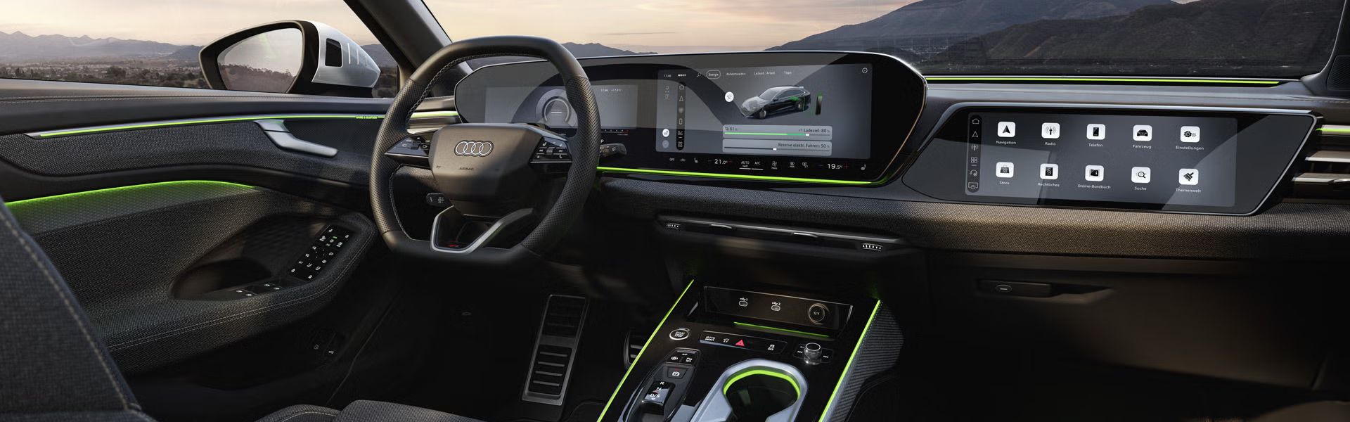 Blick auf die Displays und das Lenkrad im Cockpit des A6 Avant e-hybrid. Durch die Windschutzscheibe sind Berge zu sehen.