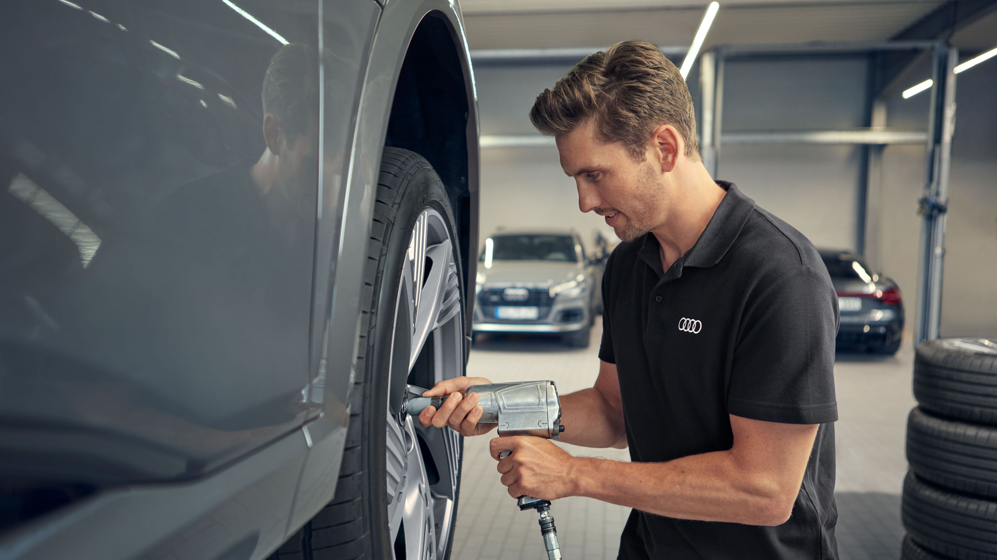 Ein Audi Service Techniker befestigt die Räder an einem Audi Elektroauto