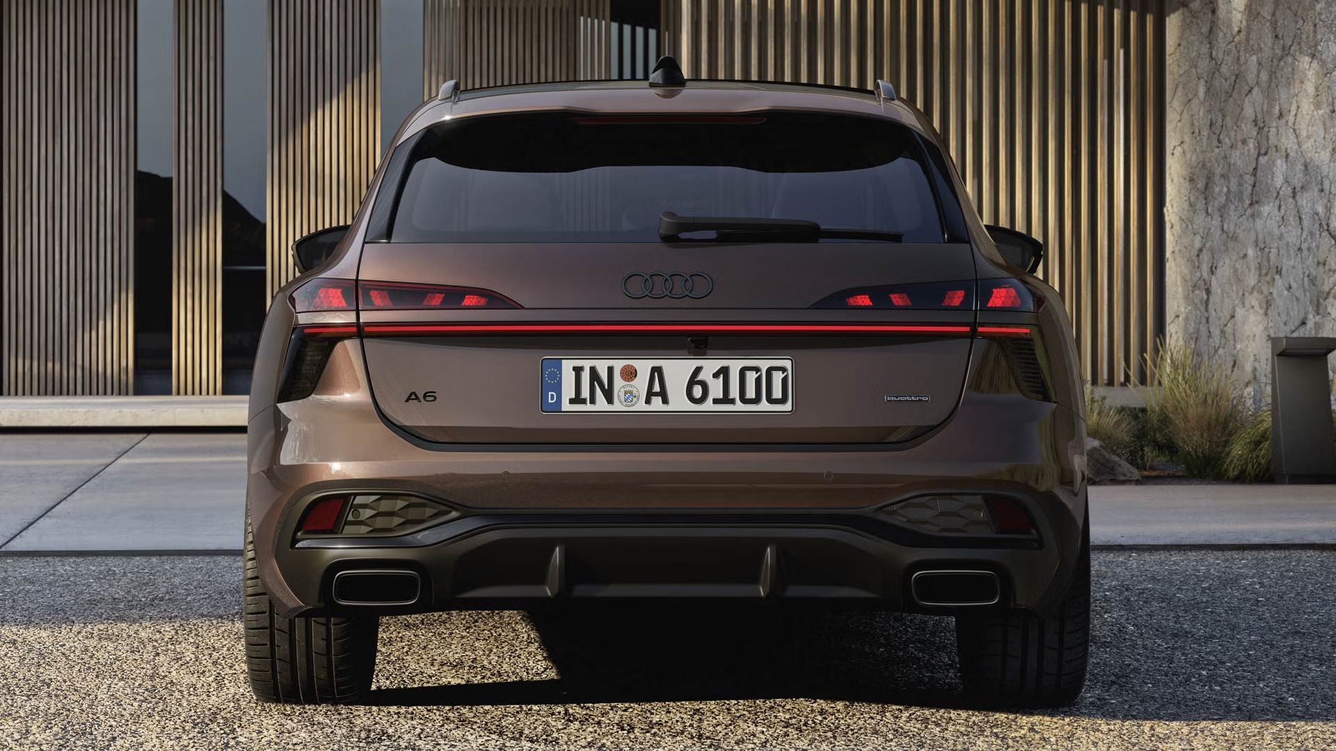 Heckaufnahme des A6 Avant, der auf einer Kiesfläche vor einer Fassade mit Holzvertäfelung und hohen Fenstern steht.