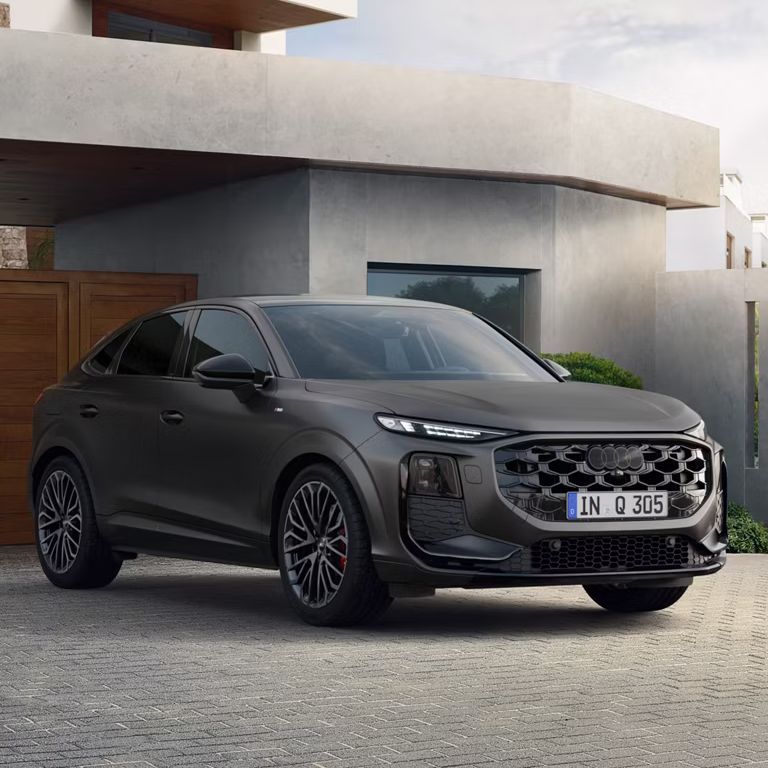 Audi Q3 Sportback in dunklem Grau steht vor einem modernen Betongebäude