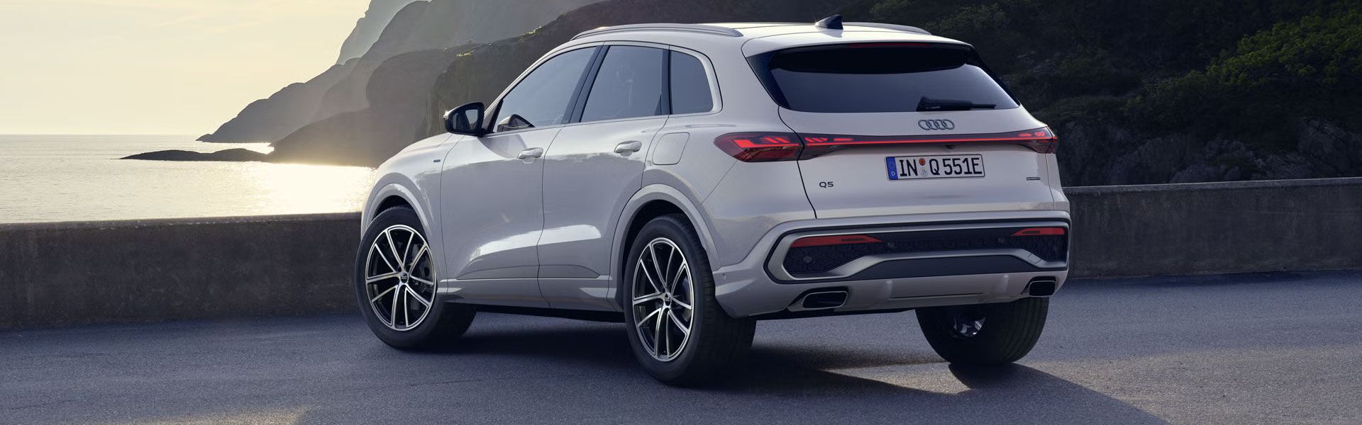 Ein weißer Q5 SUV e-hybrid steht auf einem Parkplatz an der Küste.