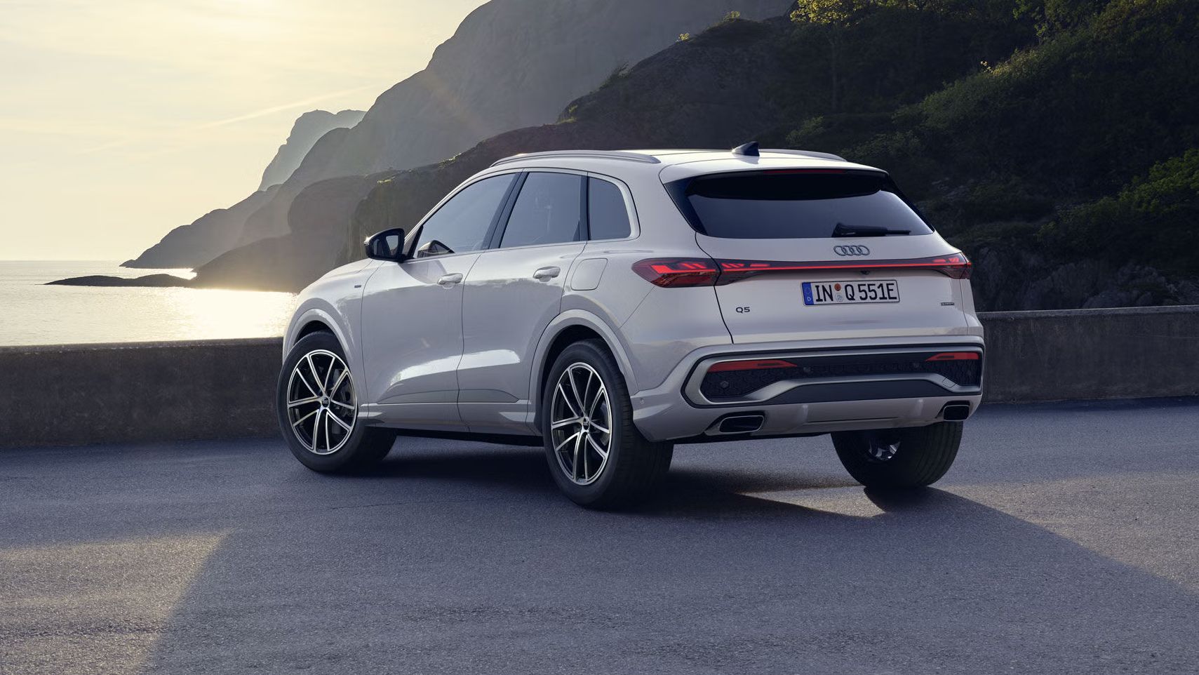 Ein weißer Q5 SUV e-hybrid steht auf einem Parkplatz an der Küste.