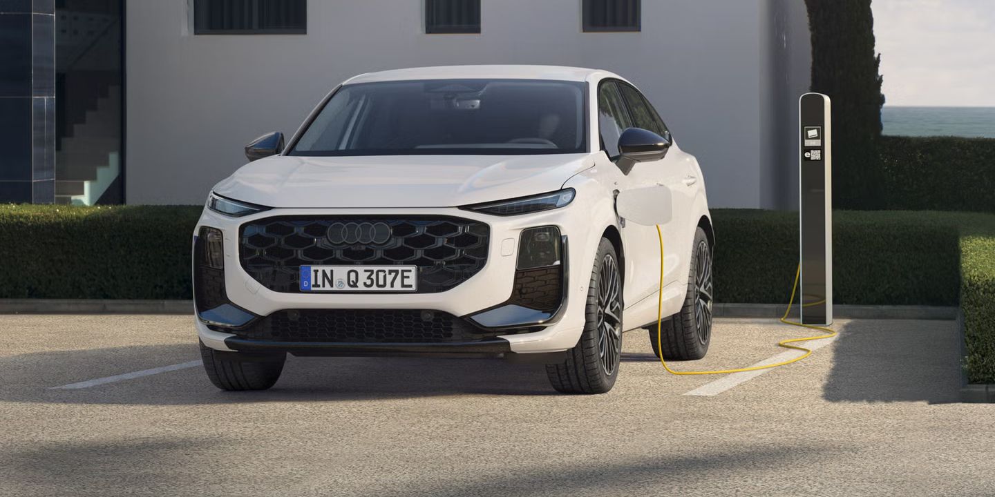 Ein weißer Q3 Sportback e-hybrid, vor einem modernen Haus parkend, lädt Strom an einer öffentlichen Ladesäule.	