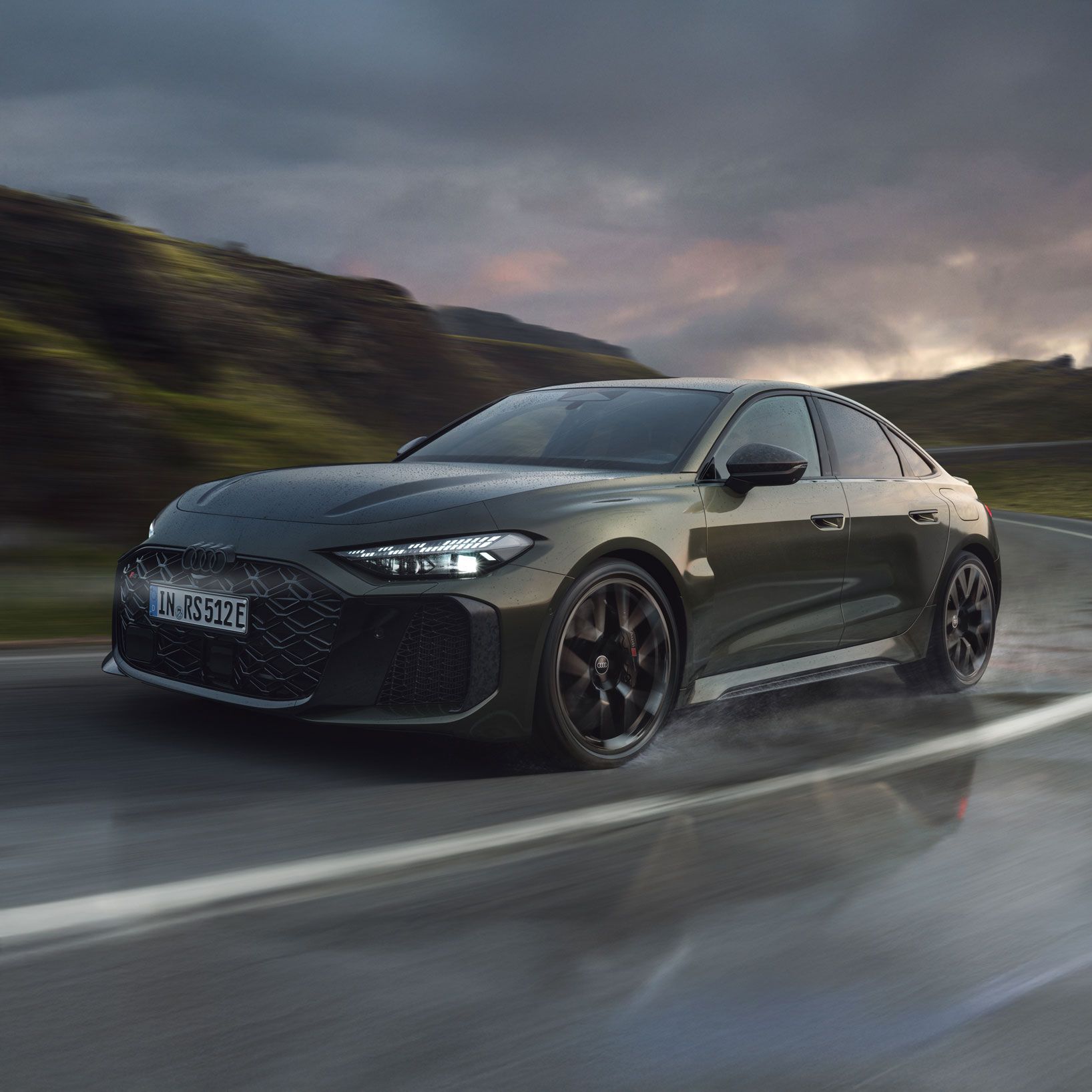 Die RS 5 Limousine schräg von vorn fährt auf einer Gebirgsstraße. Wasserdampf steigt links und rechts auf.