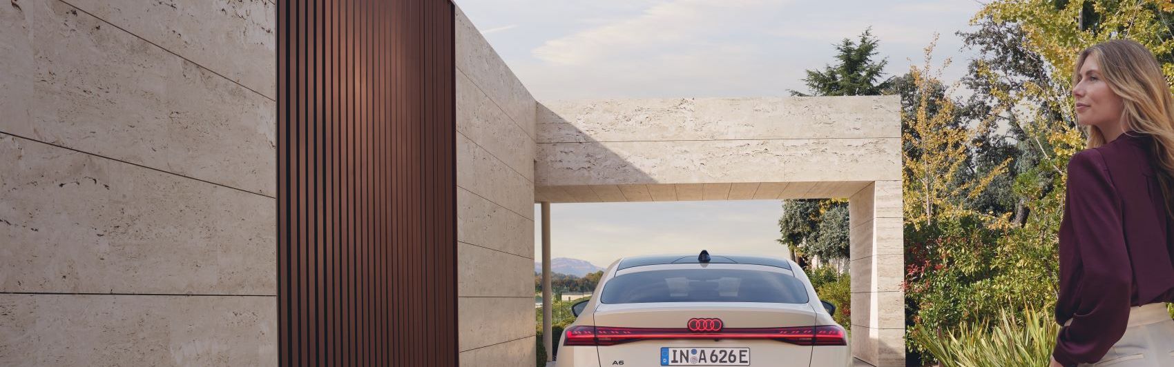 Ein weißer Audi A6 in Heckansicht parkt vor einem Haus.