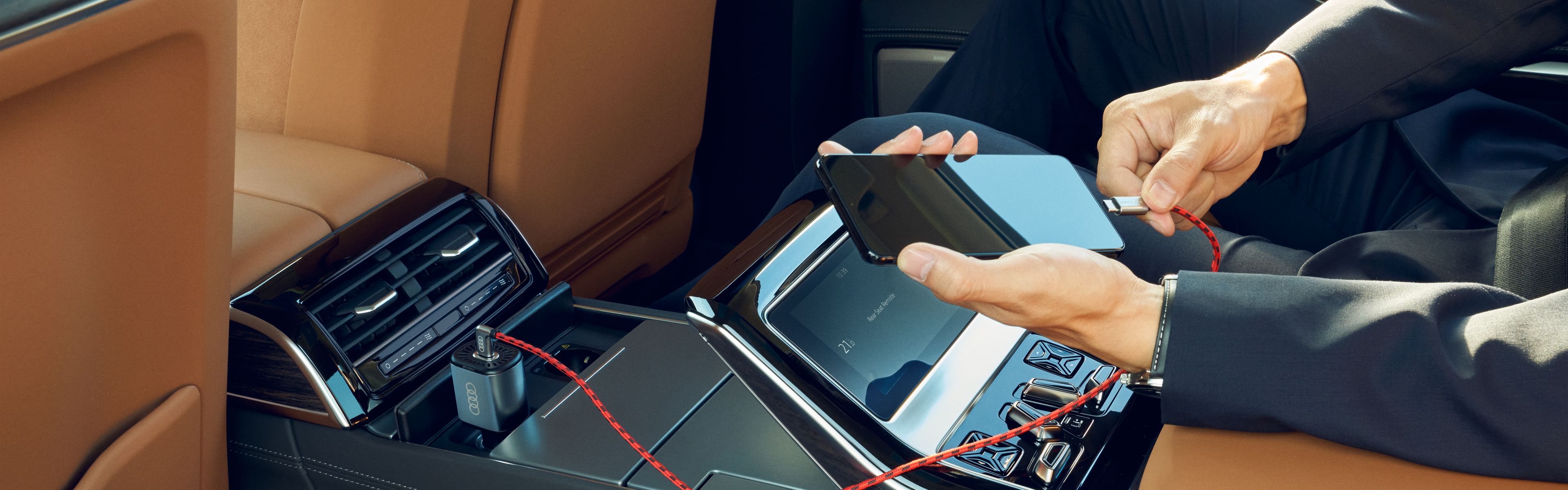 Ein Smartphone wird in einem Audi Fahrzeug an ein Ladekabel gesteckt