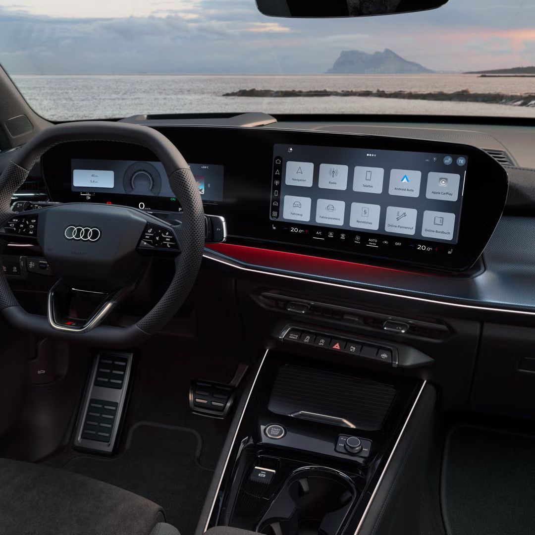 Blick von hinten auf das Cockpit des Q3 SUV mit Lenkrad, Panoramadisplay und rotem Ambiente-Lichtpaket. Durch die Frontscheibe ist das Meer zu sehen.