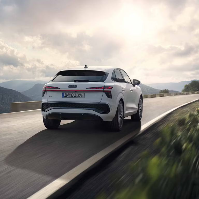 Es ist der Audi Q3 Sportback e-hybrid zu sehen der auf einer Landstraße in den Bergen fährt