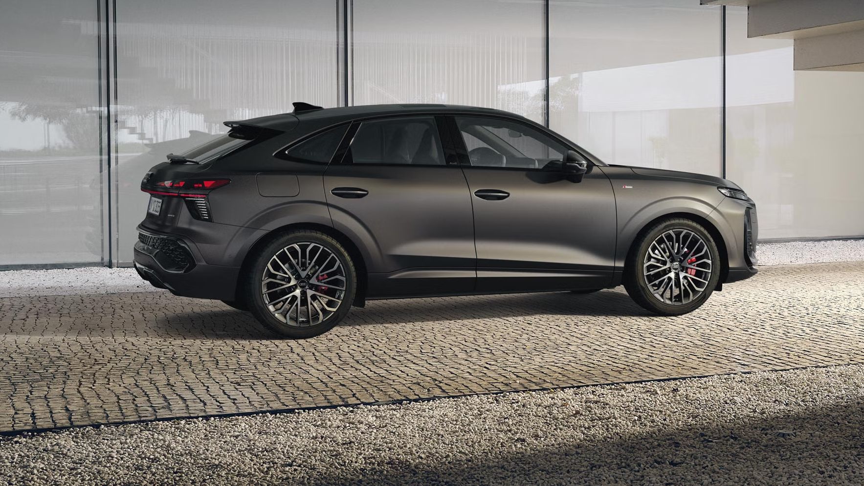 Der Q3 Sportback parkt vor dem Treppengeländer eines Gebäudes auf einem gepflasterten Weg.