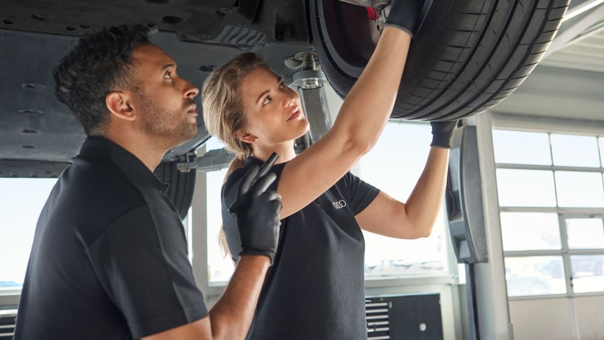 Zwei Audi Mechaniker kontrollieren die Radaufhängung bei einem Audi
