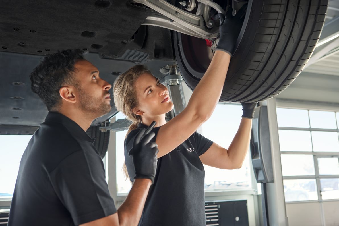 Zwei Audi Mechaniker kontrollieren die Radaufhängung bei einem Audi