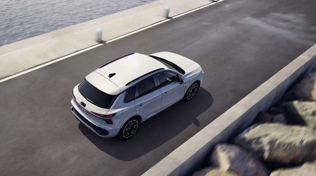 Der Q3 SUV e-hybrid fährt auf einer Straße parallel zum Meer. 	