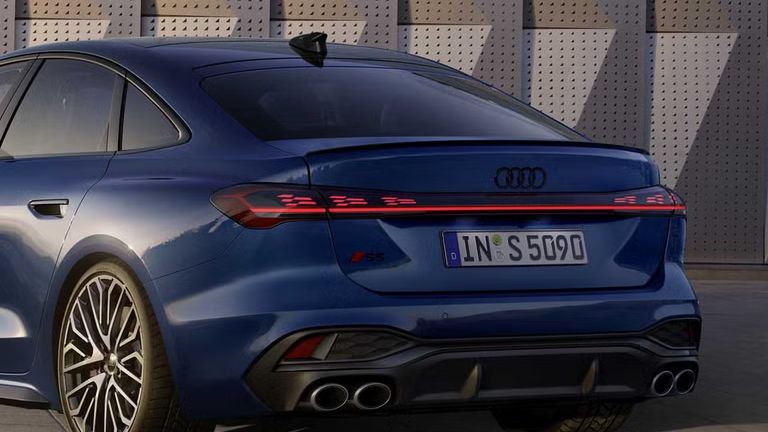 Die S5 Limousine in dunkelblau steht schräg vor einer Gebäudefassade und wird dabei vom Sonnenlicht angestrahlt.